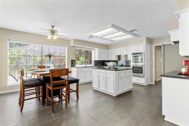 kitchen with decorative backsplash, white cabinetry, double oven, and a healthy amount of sunlight