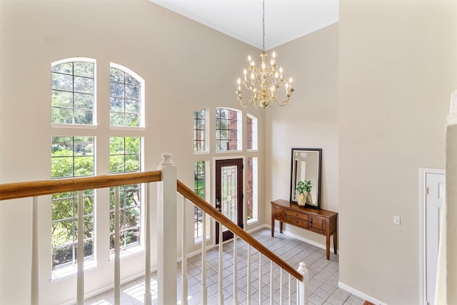 interior space featuring a high ceiling, crown molding, and a notable chandelier