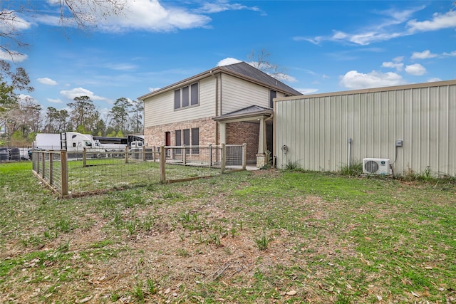 back of house with a lawn, ac unit, and an outbuilding