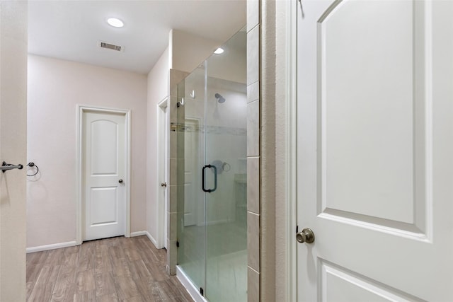 bathroom with hardwood / wood-style floors and a shower with door