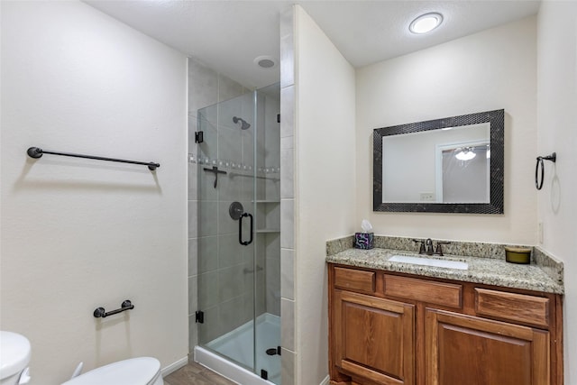 bathroom with vanity, toilet, and a shower with door