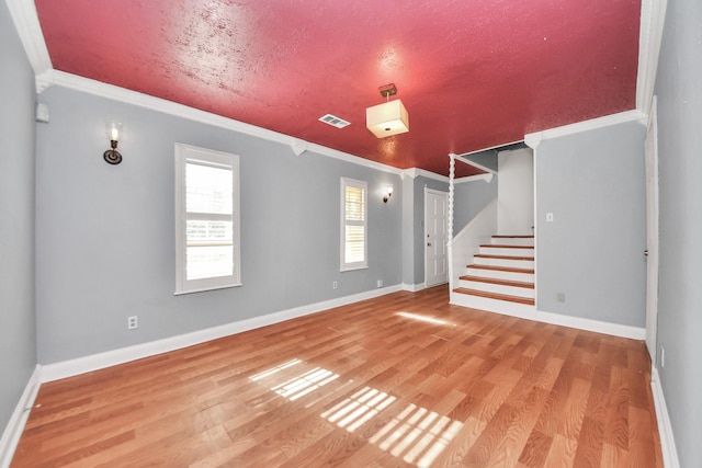 unfurnished living room featuring ornamental molding and hardwood / wood-style flooring