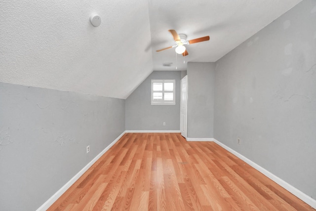 additional living space featuring ceiling fan, light hardwood / wood-style flooring, a textured ceiling, and vaulted ceiling