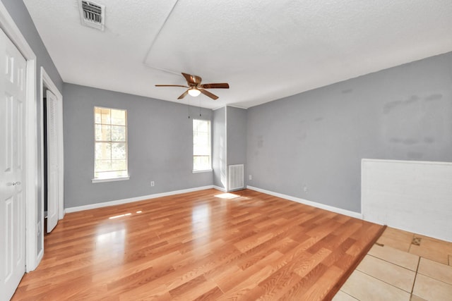 unfurnished room with a textured ceiling, light hardwood / wood-style floors, and ceiling fan