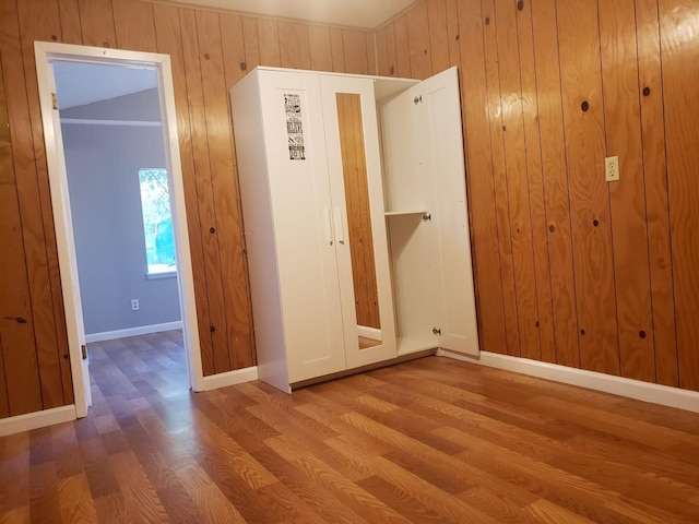 unfurnished bedroom featuring wooden walls and hardwood / wood-style floors