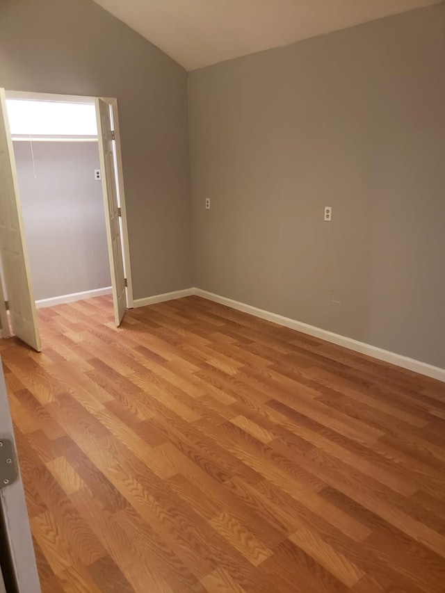 spare room featuring light hardwood / wood-style floors and lofted ceiling