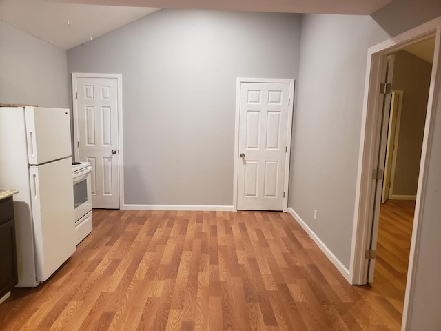 kitchen featuring vaulted ceiling, light hardwood / wood-style floors, and white appliances