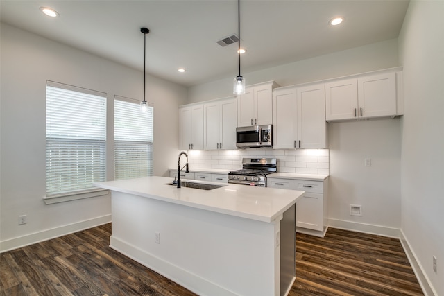 kitchen featuring appliances with stainless steel finishes, a kitchen island with sink, sink, pendant lighting, and white cabinets