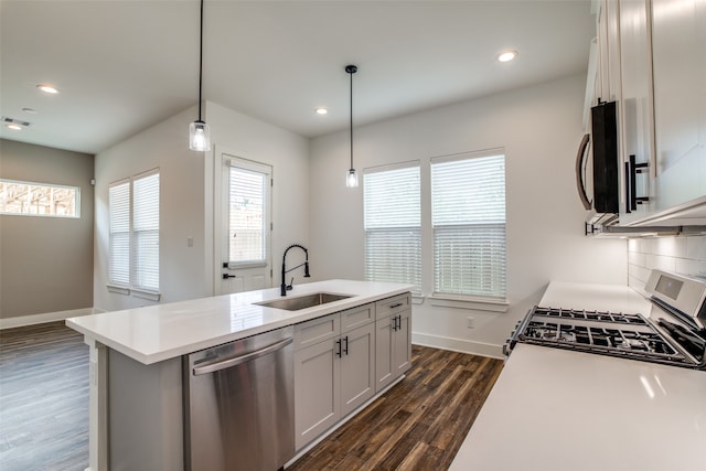 kitchen featuring sink, hanging light fixtures, stainless steel dishwasher, stove, and a kitchen island with sink