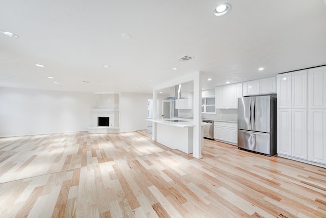 unfurnished living room with a large fireplace and light hardwood / wood-style floors