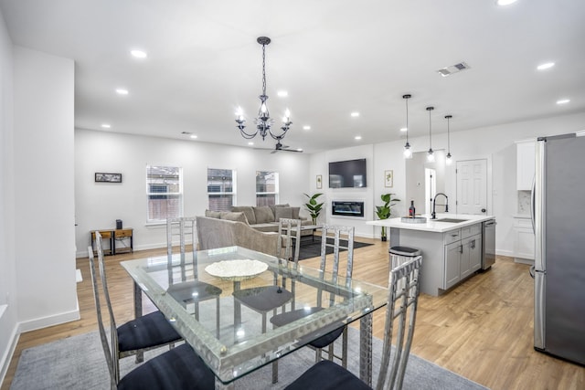 dining space featuring a chandelier, light wood-type flooring, and sink