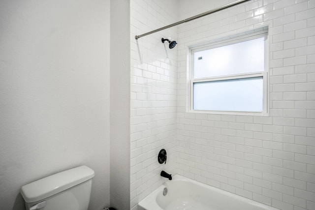 bathroom featuring toilet and tiled shower / bath