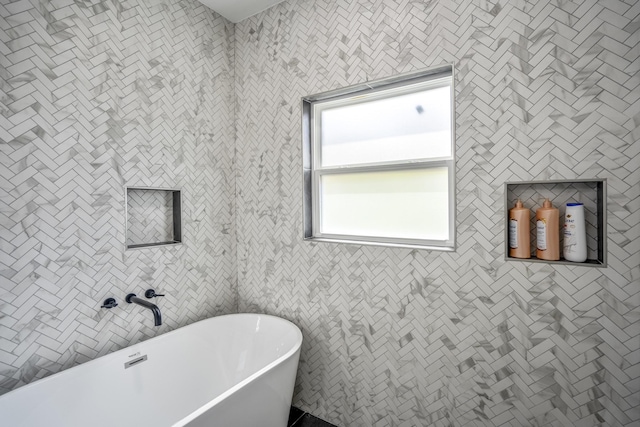 bathroom featuring a bath and tile walls