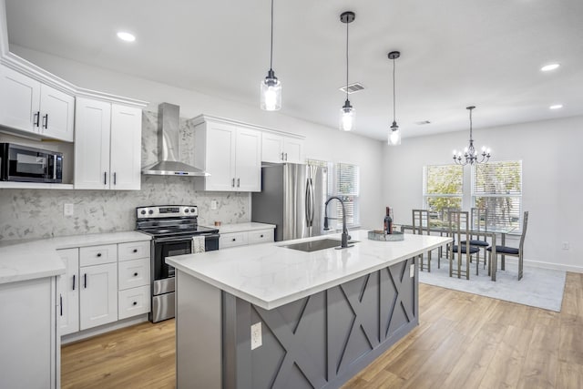 kitchen featuring pendant lighting, white cabinets, stainless steel appliances, and wall chimney range hood