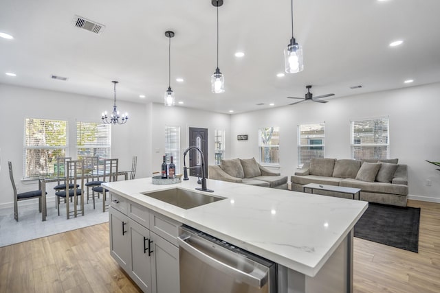 kitchen featuring dishwasher, decorative light fixtures, a kitchen island with sink, and sink