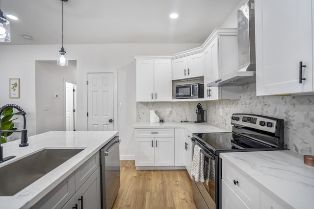 kitchen featuring white cabinetry, sink, light hardwood / wood-style flooring, decorative light fixtures, and appliances with stainless steel finishes