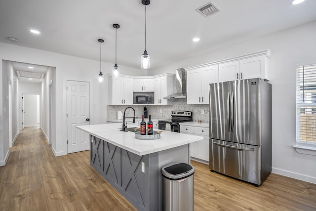 kitchen featuring white cabinets, appliances with stainless steel finishes, and wall chimney range hood