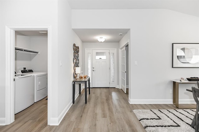 foyer entrance with light hardwood / wood-style floors, washing machine and dryer, and vaulted ceiling