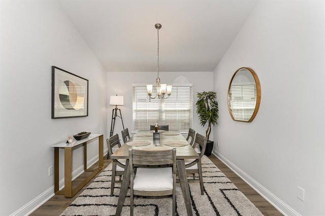 dining space with a chandelier, vaulted ceiling, and dark wood-type flooring