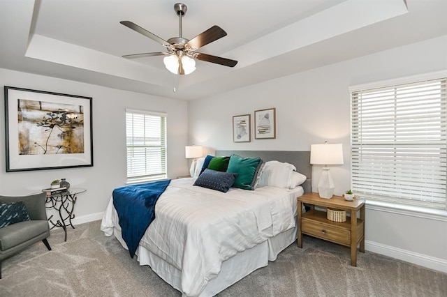 carpeted bedroom with a tray ceiling and ceiling fan