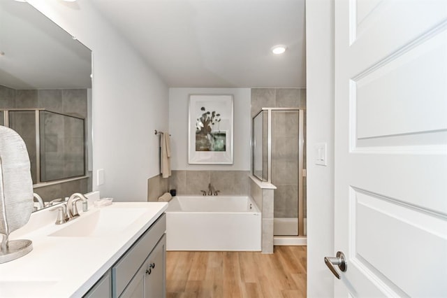 bathroom with plus walk in shower, vanity, and hardwood / wood-style flooring