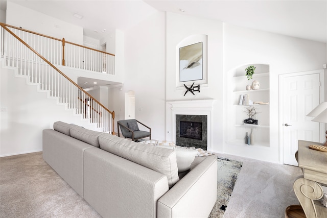 living room with built in features, light carpet, a high ceiling, and a premium fireplace