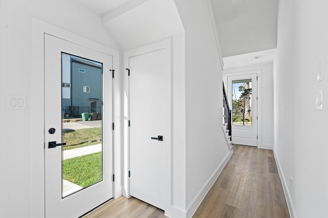 foyer with light wood-type flooring and vaulted ceiling