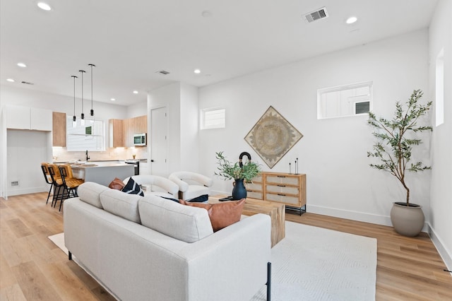 living room with light hardwood / wood-style floors, a wealth of natural light, and sink