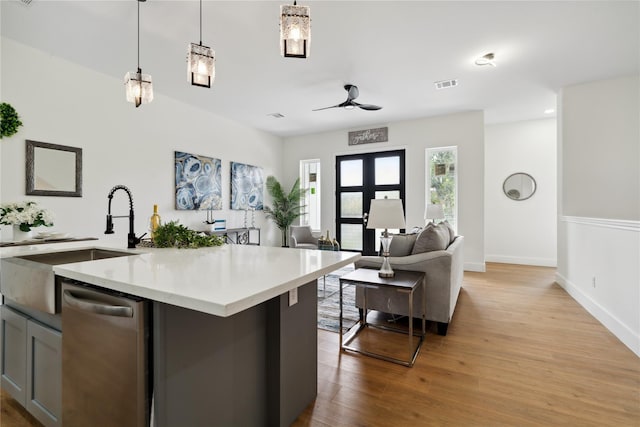 kitchen featuring pendant lighting, light countertops, visible vents, stainless steel dishwasher, and a sink