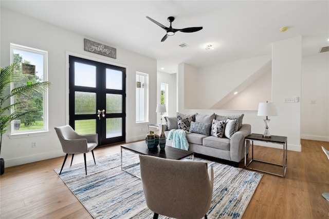 living room featuring light wood-style floors, baseboards, visible vents, and french doors