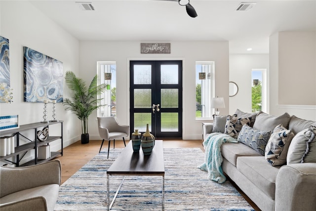 living room featuring french doors, light wood-style flooring, visible vents, and baseboards