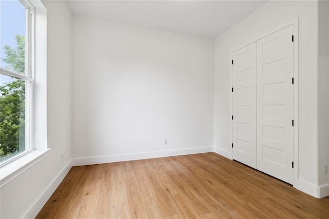 unfurnished bedroom with light wood-type flooring, baseboards, and a closet