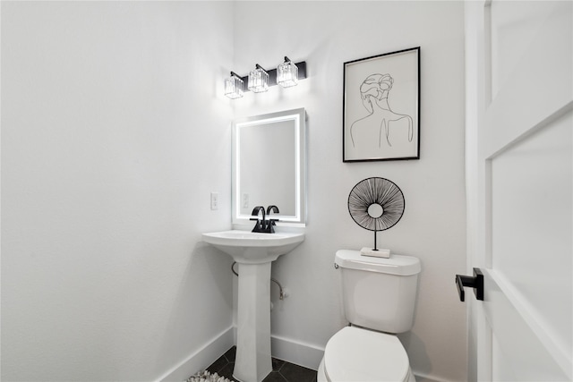 half bath featuring tile patterned flooring, toilet, and baseboards