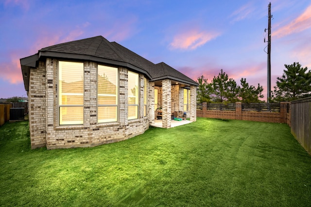 back house at dusk with a yard and a patio