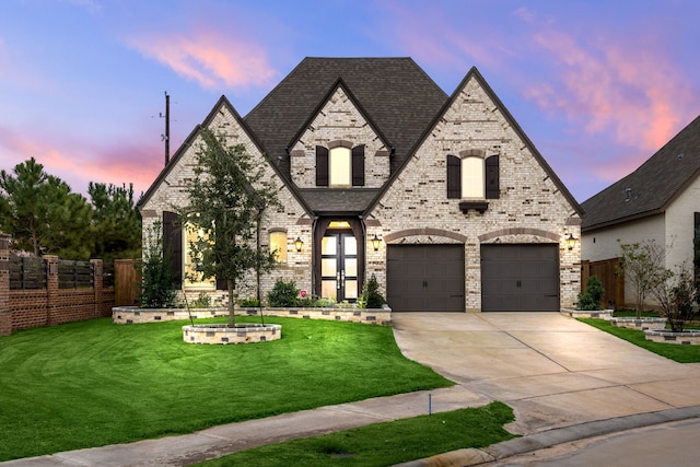 french country inspired facade with a yard and a garage