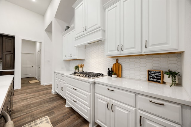 kitchen featuring light stone countertops, decorative backsplash, dark hardwood / wood-style flooring, stainless steel gas cooktop, and white cabinetry