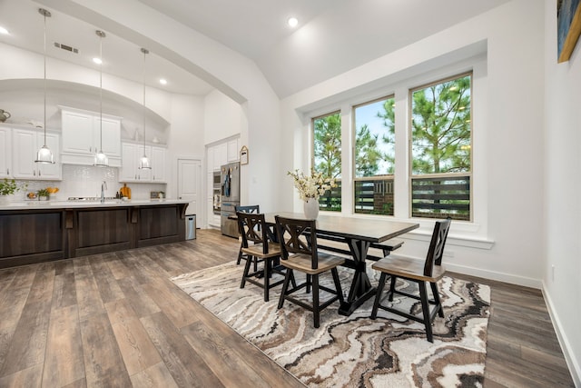 dining room featuring dark hardwood / wood-style floors, sink, and vaulted ceiling