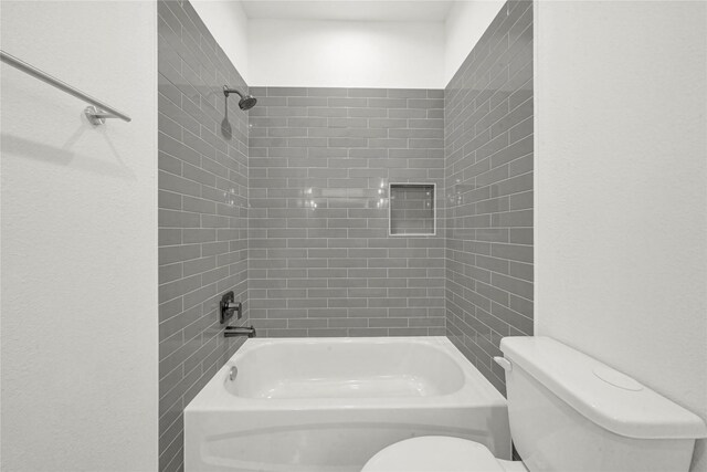 bathroom with toilet and tiled shower / bath