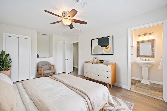 bedroom with light wood-type flooring, ensuite bathroom, and ceiling fan