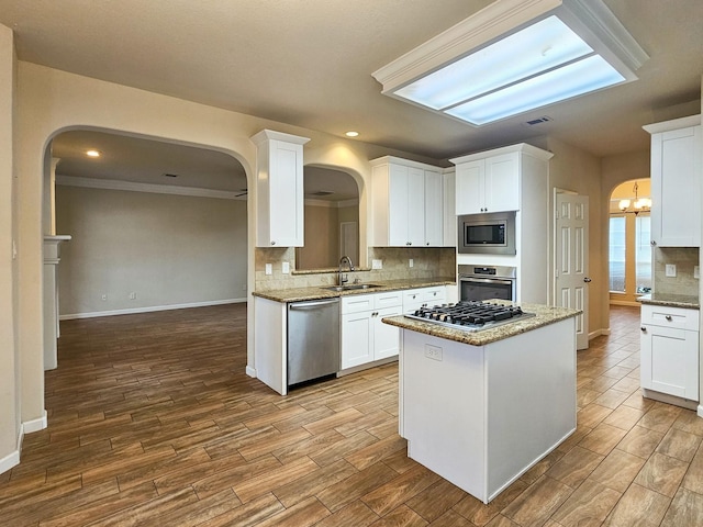 kitchen featuring light stone countertops, decorative backsplash, stainless steel appliances, sink, and white cabinetry