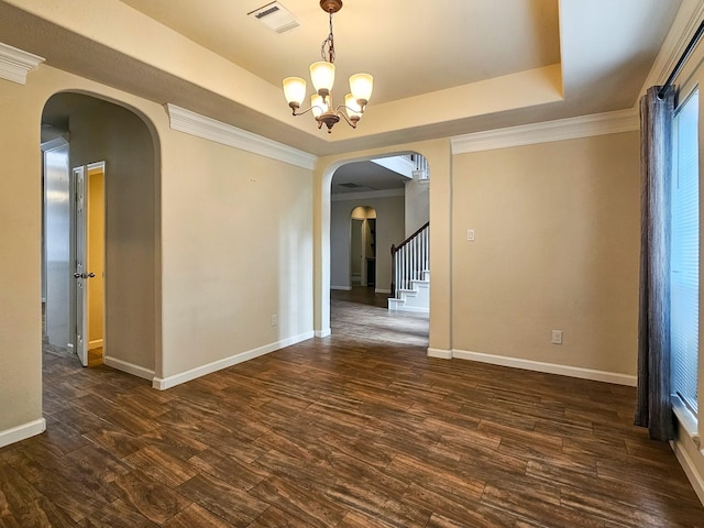 spare room featuring a raised ceiling, crown molding, dark hardwood / wood-style flooring, and a chandelier