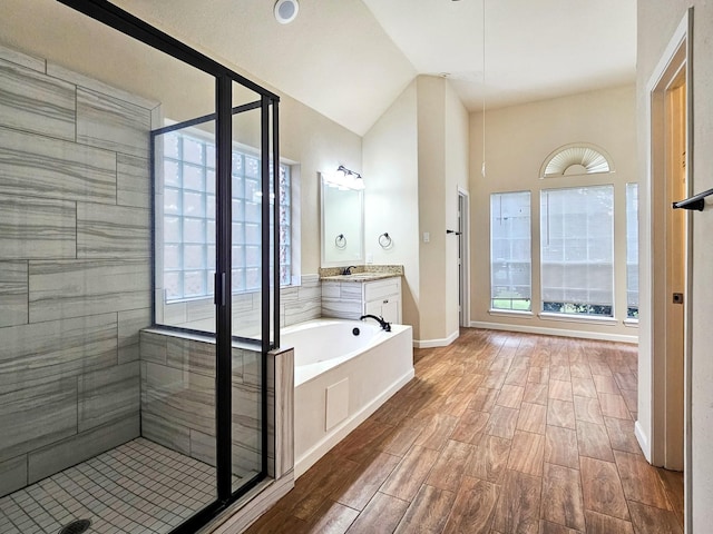 bathroom with plus walk in shower, vanity, and lofted ceiling