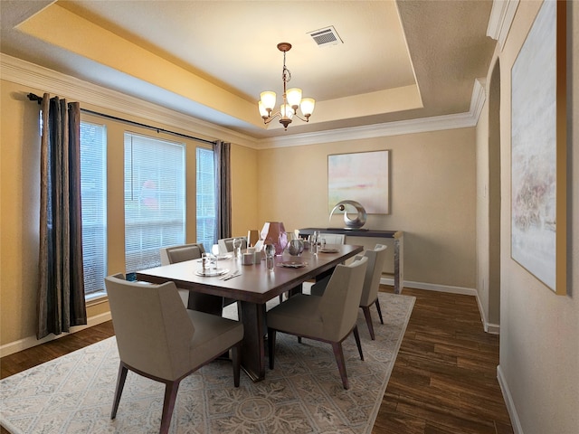 dining area with a notable chandelier, a raised ceiling, and dark wood-type flooring