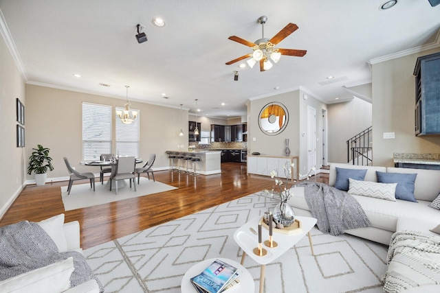 living room with hardwood / wood-style floors, ceiling fan with notable chandelier, and crown molding