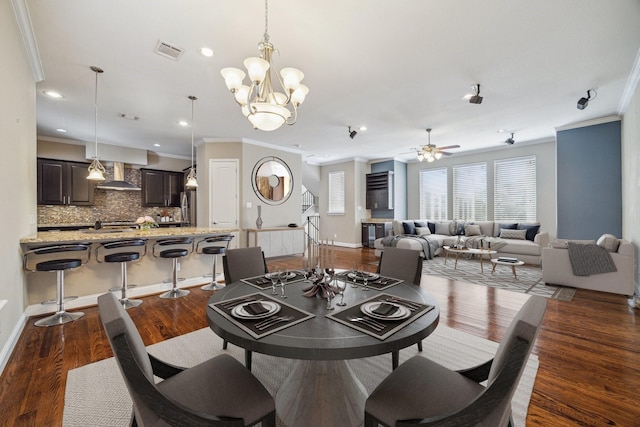 dining space with ceiling fan with notable chandelier, dark hardwood / wood-style flooring, and ornamental molding