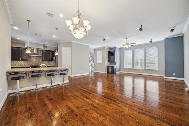 unfurnished living room with ceiling fan with notable chandelier, dark hardwood / wood-style floors, and crown molding