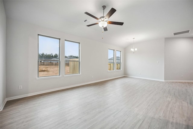 empty room with ceiling fan with notable chandelier, vaulted ceiling, and light wood-type flooring