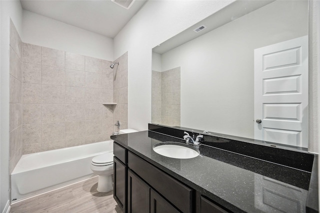 full bathroom featuring tiled shower / bath combo, toilet, wood-type flooring, and vanity