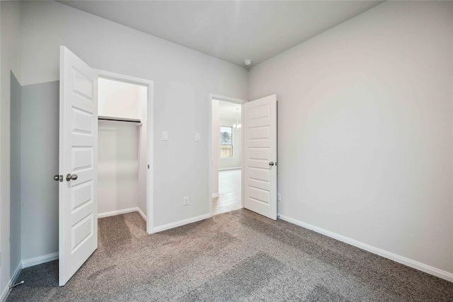 unfurnished bedroom featuring a walk in closet, carpet floors, and a closet