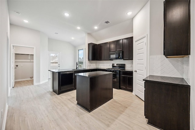 kitchen with a center island, sink, backsplash, lofted ceiling, and black appliances